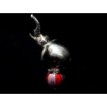 A miniature silver elephant balancing on a ball, the ball with red enamelled decoration,