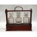 Early 20th century oak and brass tantalus - A hobnail decorated set of three glass decanters and