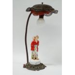 1920s Table Lamp - A Rococo gilt brass based electric lamp with a hand painted western woman dressed