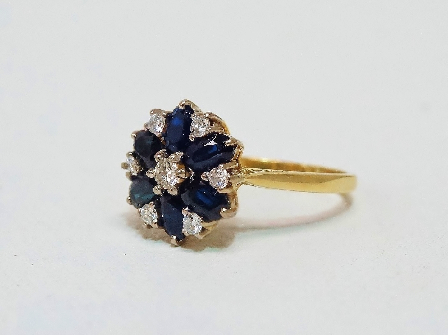 A sapphire and diamond floral shaped cluster ring - set in 18ct yellow gold, size M, weight 4.1g.