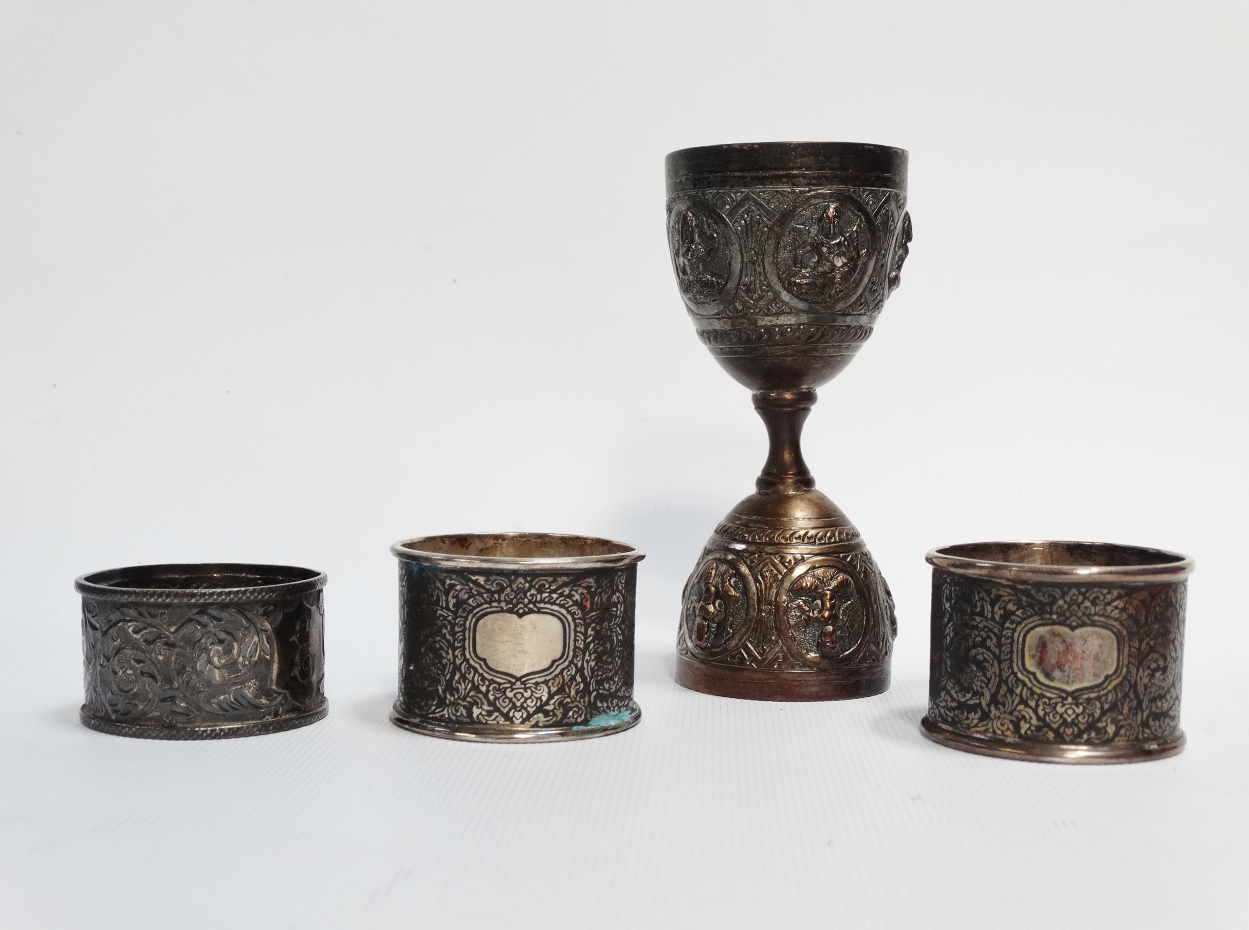 An Indian silver double egg cup - Repousse decorated with deities, 10cm (high), together with a pair