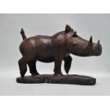 A carved exotic hardwood model of a warthog - standing on a naturalistic base, signed Nganga, height