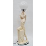 An Art Deco table lamp - the plaster base modelled as a nude supporting a white glass globe,