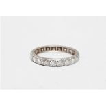 A diamond eternity ring - the round cut stones set within a white metal band, probably platinum,