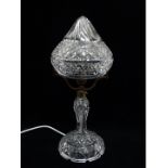 An early 20th century clear cut glass table lamp - the conical cover supported by brass fittings