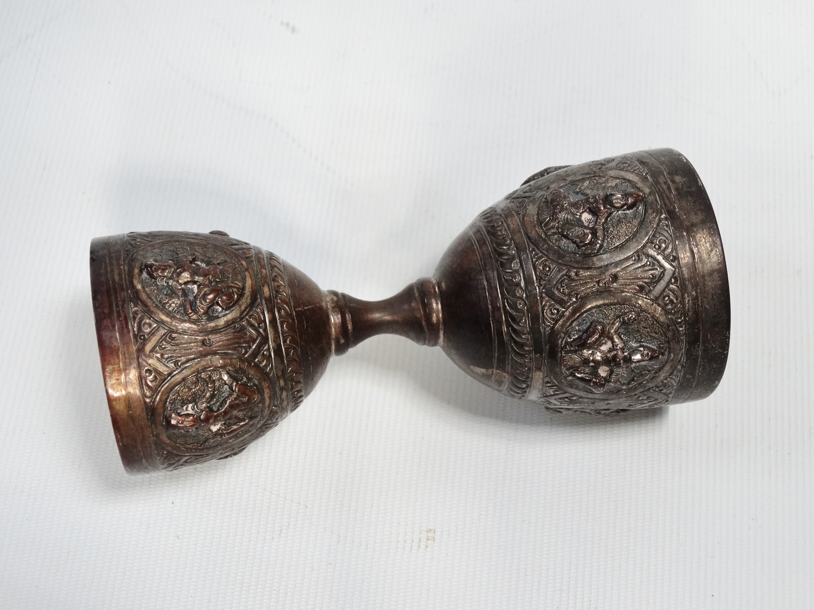 An Indian silver double egg cup - Repousse decorated with deities, 10cm (high), together with a pair - Image 3 of 7