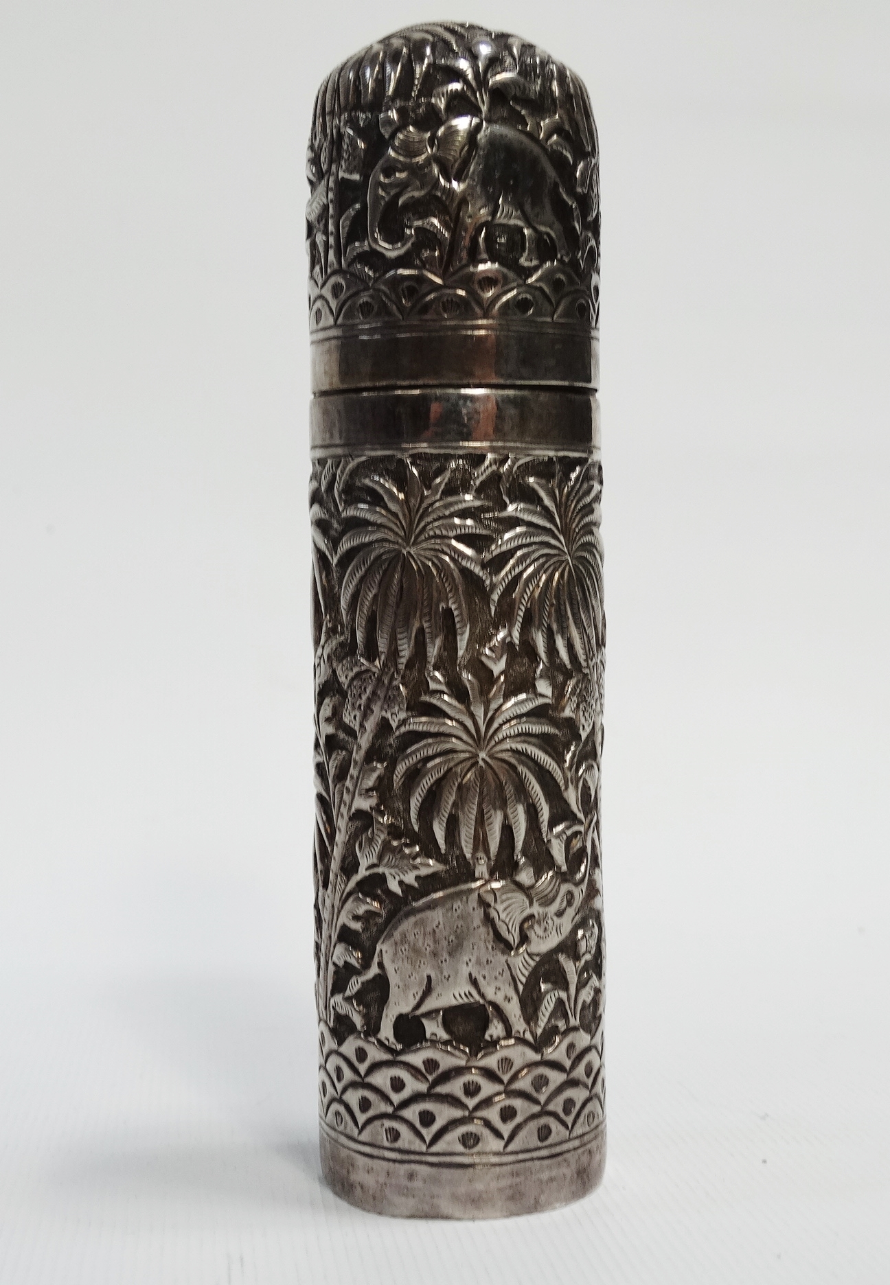 An Indian silver cylindrical box - Repousse decorated with elephants, tigers and stag in a palm
