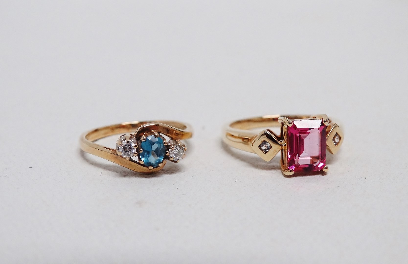 A pink tourmaline and diamond dress ring - the emerald cut central stone flanked by diamonds on a