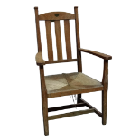 An Arts and Crafts oak open armchair in the manner of Charles Francis Annesley Voysey - the top rail