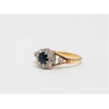 A sapphire and diamond ring - the circular faceted central stone within a band of diamonds and