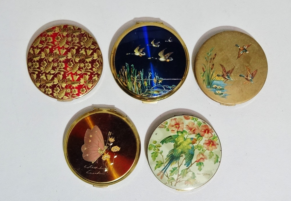 A Stratton compact - decorated with a parrot among flowers, together with four other compacts (5)