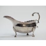 A Georgian silver sauce boat - London, date indistinct, with scalloped rim and raised on three pad