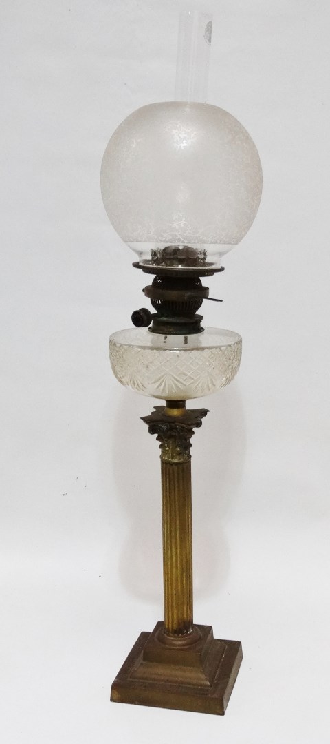 A Victorian brass oil lamp - the clear cut glass reservoir and etched glass globe, on a brass