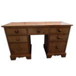 A 20th century pine kneehole desk - the rectangular top above an arrangement of seven drawers with