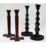 A pair of mid 20th century mahogany candlesticks - of faceted form tapering to a cruciform base,