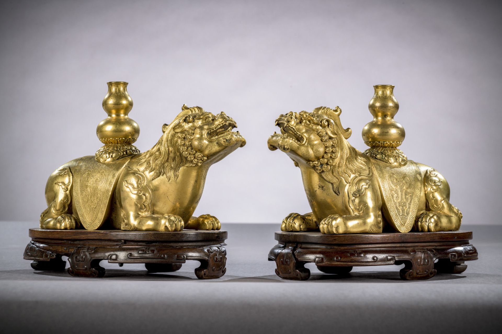 A fine pair of gilt bronze mythical lions on hardwood stands, China Qing dynasty (14.5 x 22.5 x 10