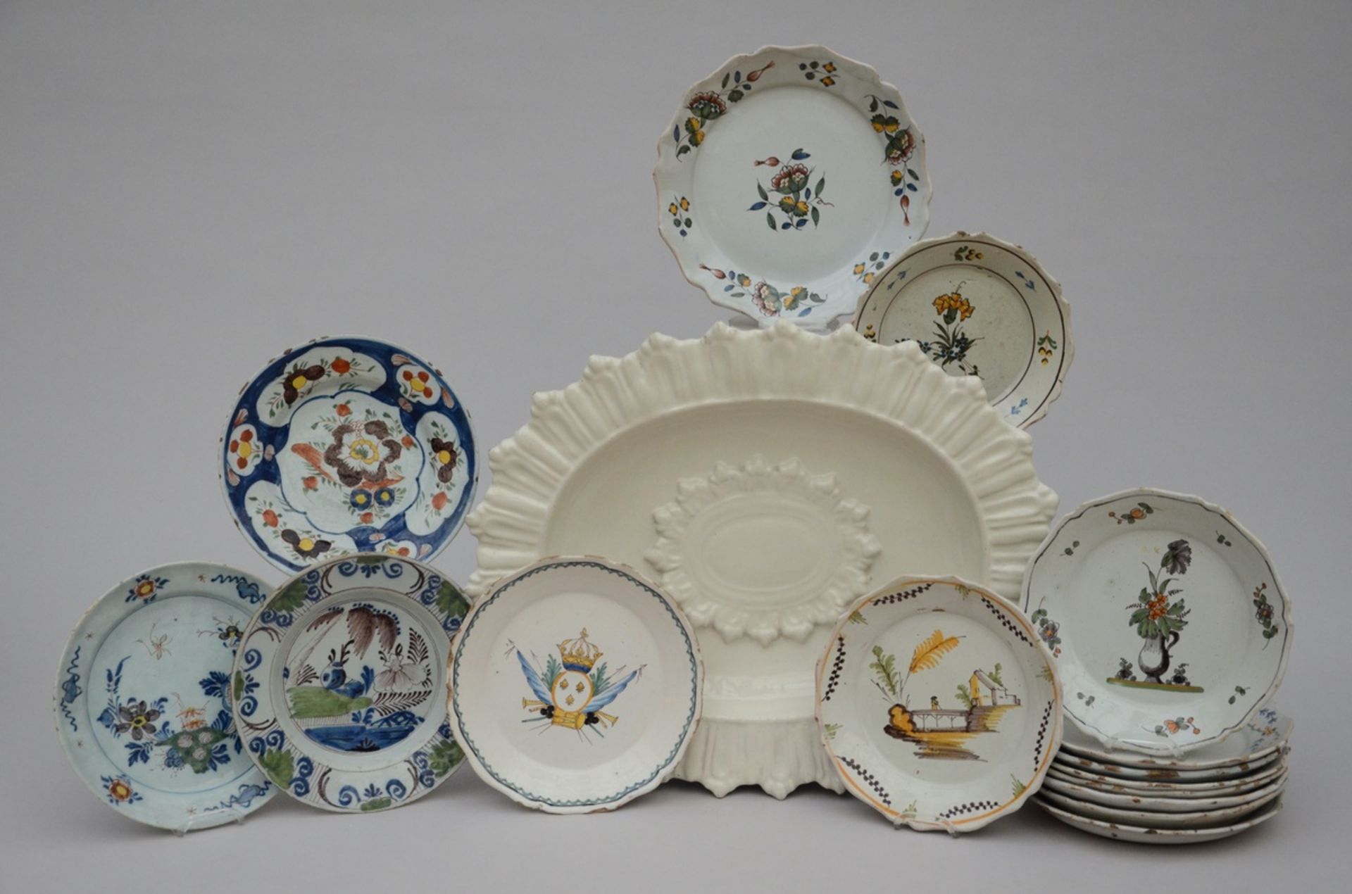 Lot: charger (43x53x6cm) and 15 plates in faience (from dia 20 to 25cm) (*)