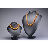 An amber coloured graduated spherical bead necklace with screw clasp together with a graduated amber