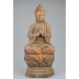 A Chinese carved wooden Buddha. The figure seated upright on raised lotus base with hands clasp in