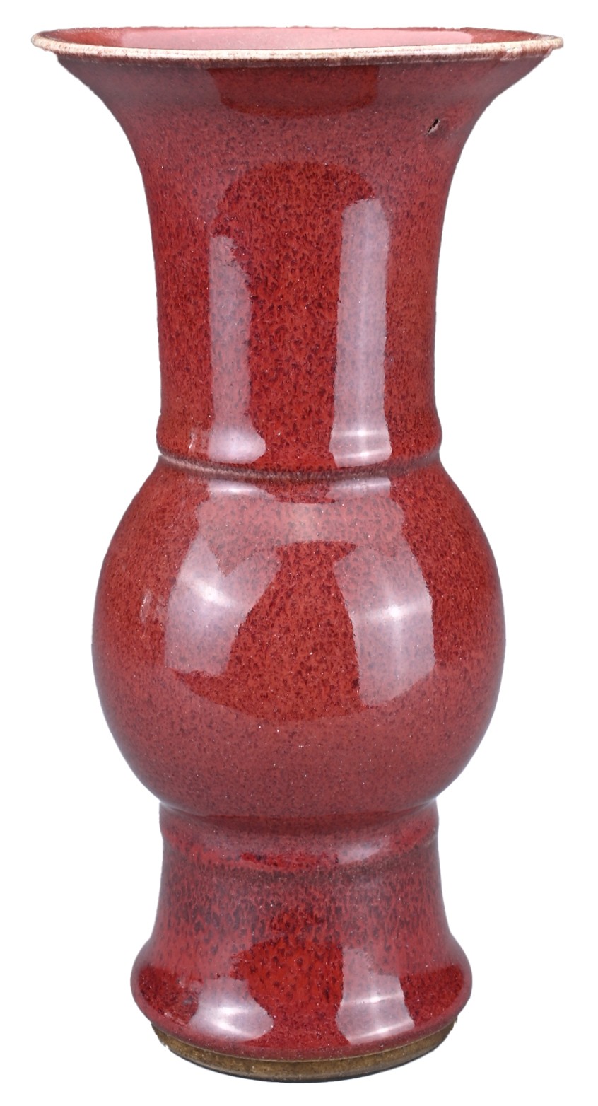 A CHINESE SANG-DE-BOEUF PORCELAIN GU-FORM BEAKER VASE. Covered in a dark red speckled glaze thinning