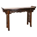 A CHINESE ELM ALTAR TABLE, 20TH CENTURY. The rectangular top with typical scroll-form ends, a