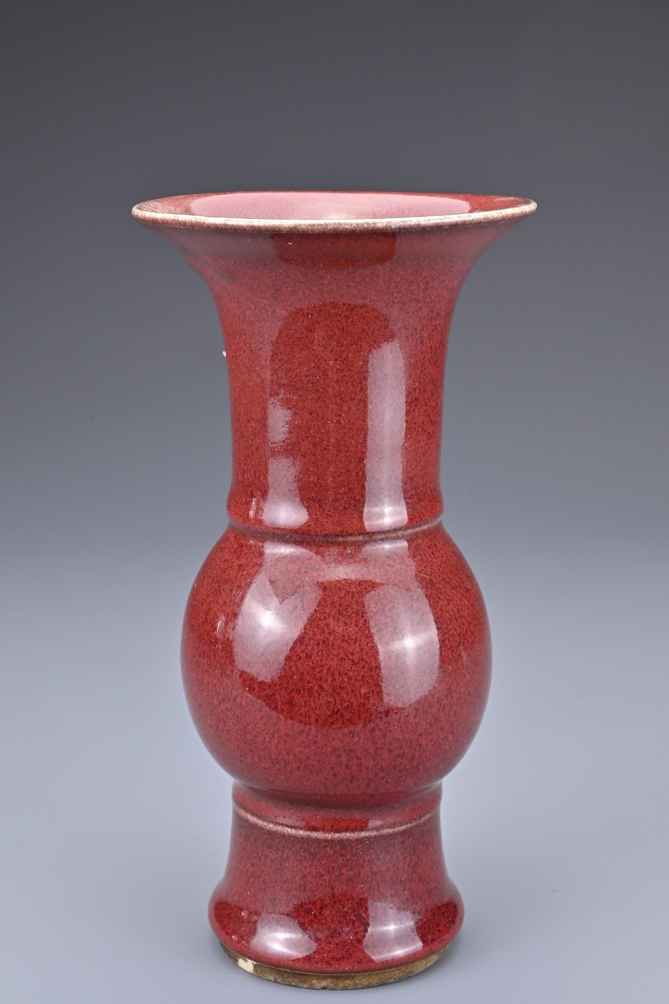 A CHINESE SANG-DE-BOEUF PORCELAIN GU-FORM BEAKER VASE. Covered in a dark red speckled glaze thinning - Image 4 of 7