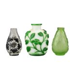 THREE CHINESE GLASS SNUFF BOTTLES. Comprising a green-overlay white glass bottle with floral