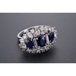 A PLATINUM, DIAMOND AND SAPPHIRE DRESS RING. Three oval cut sapphires surrounded by six baguette,