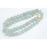 A PALE GREEN JADEITE SINGLE STRAND BEADED NECKLACE WITH 18KT YELLOW GOLD CLASP. The marquise-
