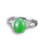 AN 18KT WHITE GOLD, DIAMOND AND JADEITE RING. An oval shaped cabochon mounted in white gold and