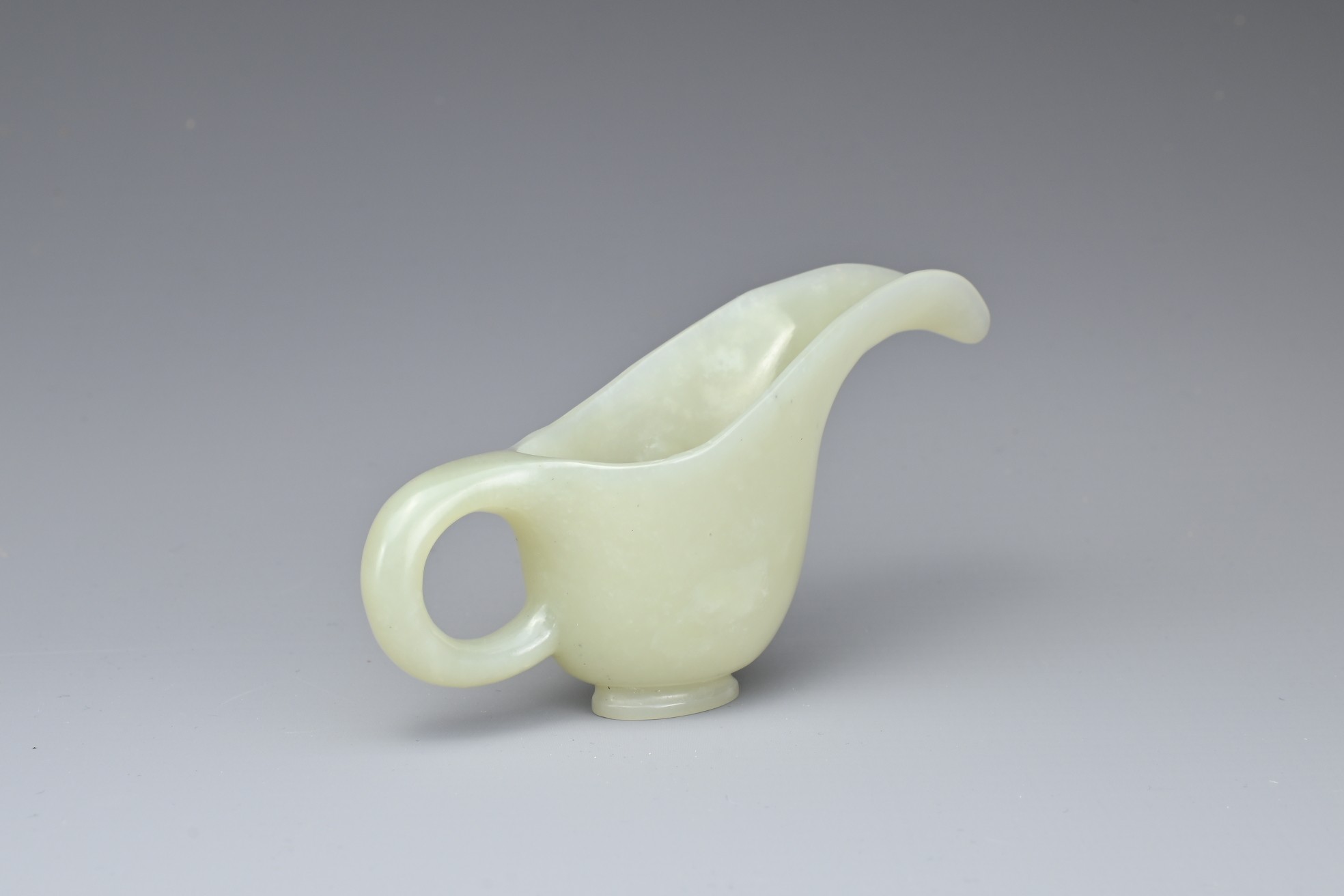 A CHINESE PALE CELADON JADE CUP. Of slender form with a looped handle and curved spout. 10.5cm - Image 4 of 7