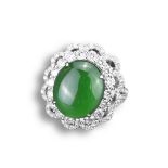 AN 18CT WHITE GOLD, DIAMOND AND JADEITE DRESS RING. An oval shaped cabochon mounted in white gold