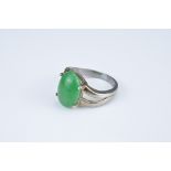 AN 18KT WHITE GOLD MOUNTED GREEN STONE OVAL CABOCHON SET RING. With claw setting, between pierced