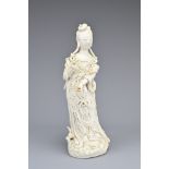 A CHINESE BLANC DE CHINE FIGURE OF GUANYIN, 17/18TH CENTURY. The figure standing on a dragon carp