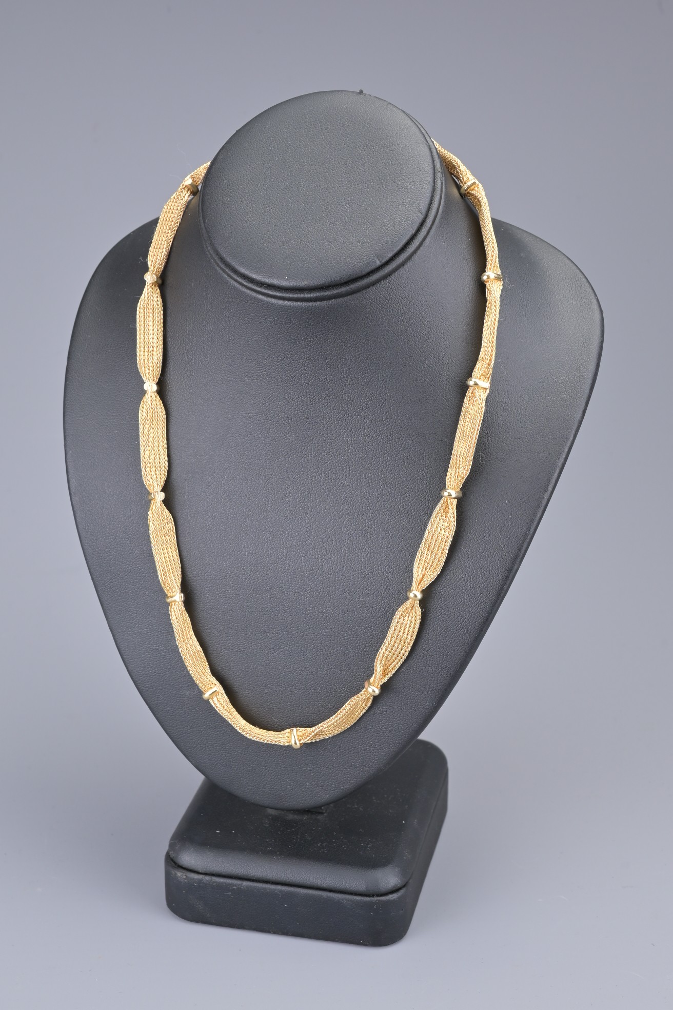 AN ANTIQUE 18CT YELLOW GOLD NECKLACE. The necklace with flat mesh design with fifteen clamped