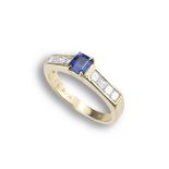 AN 18CT DIAMOND AND SAPPHIRE DRESS RING. Emerald cut 0.63ct sapphire set in 18ct yellow gold with