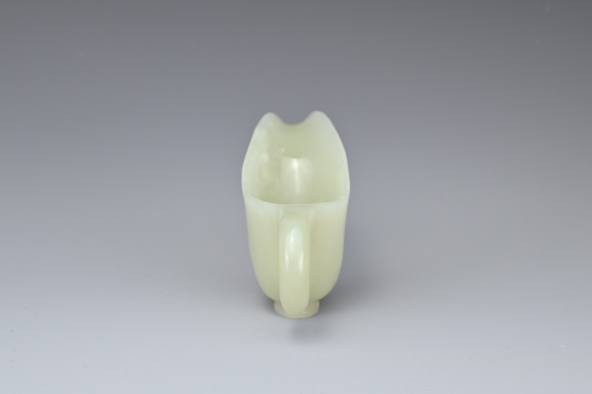 A CHINESE PALE CELADON JADE CUP. Of slender form with a looped handle and curved spout. 10.5cm - Image 5 of 7