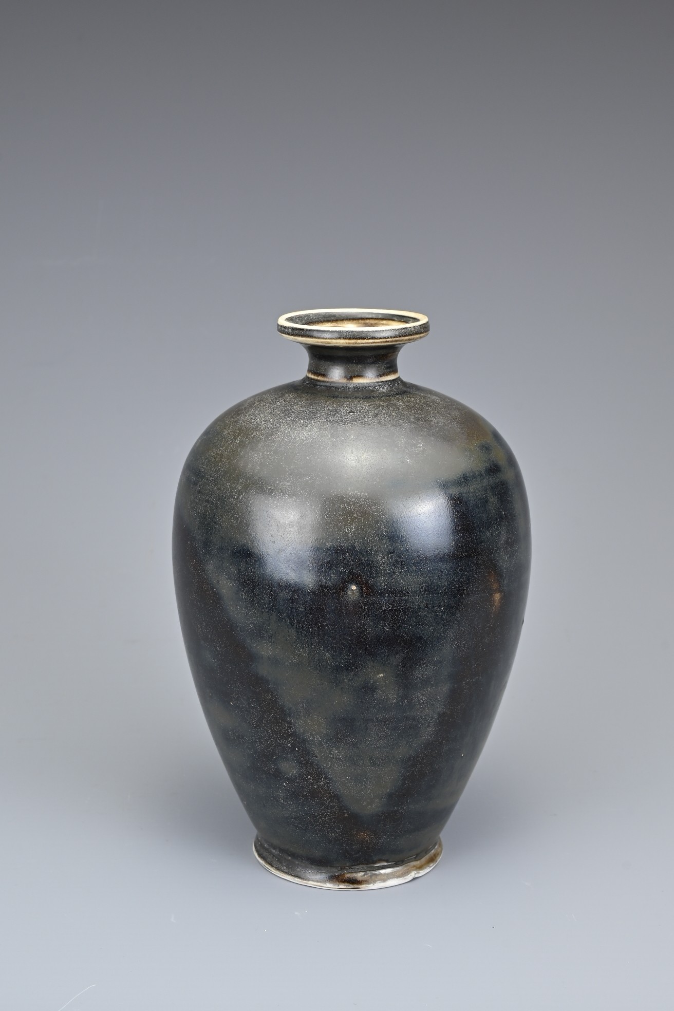 A CHINESE DING TYPE BROWN GLAZED BOTTLE VASE. Of ovoid form with everted rim covered in a dark brown