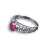 AN 18KT WHITE GOLD, RUBY AND DIAMOND SET RING. The oval ruby in claw setting with three bands of