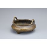 A CHINESE BRONZE TRIPOD CENSER. Of squat circular form with two looped handles on three conical