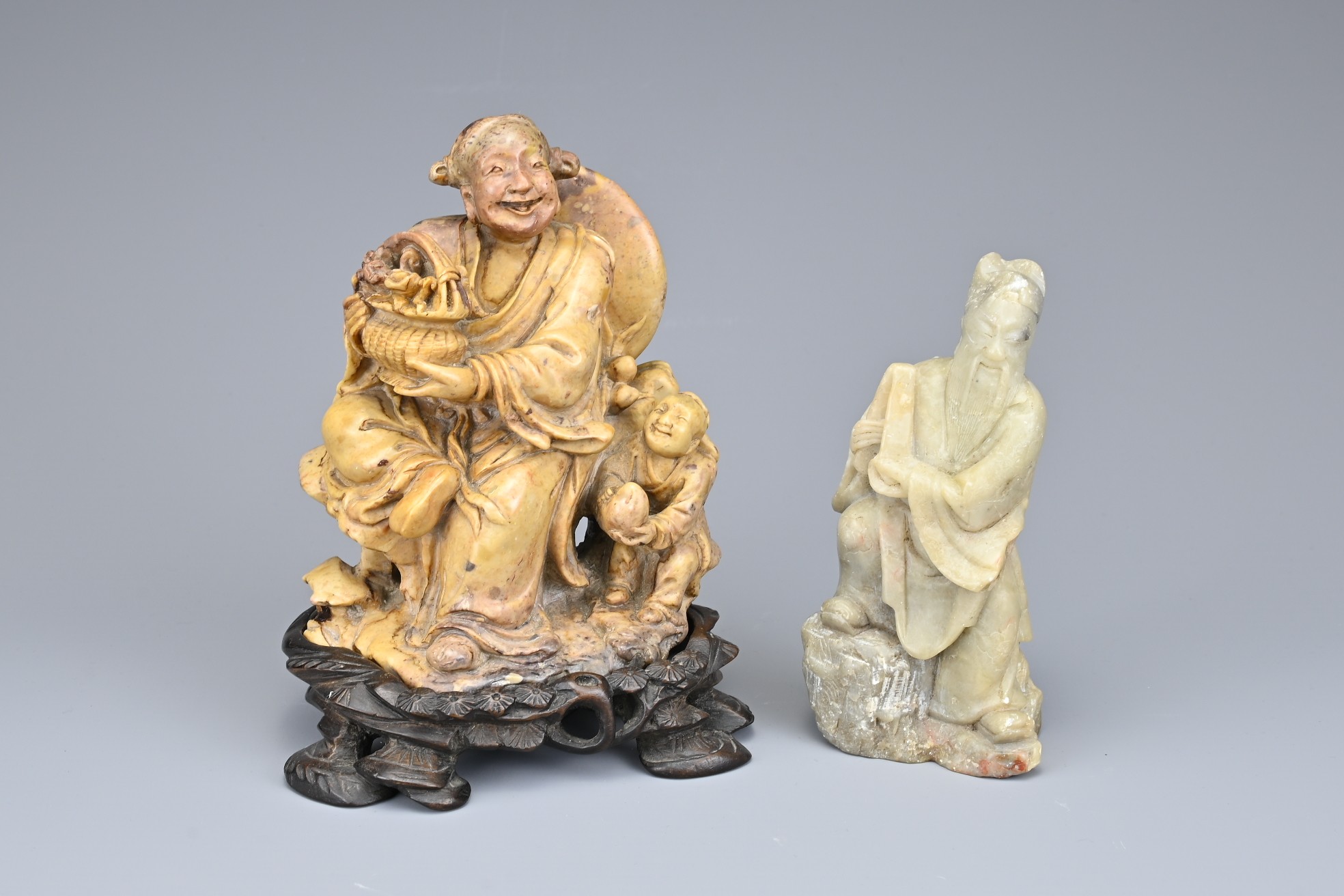 TWO CHINESE SOAPSTONE CARVINGS OF IMMORTALS, EARLY 20TH CENTURY. To include a carved figure of Lan