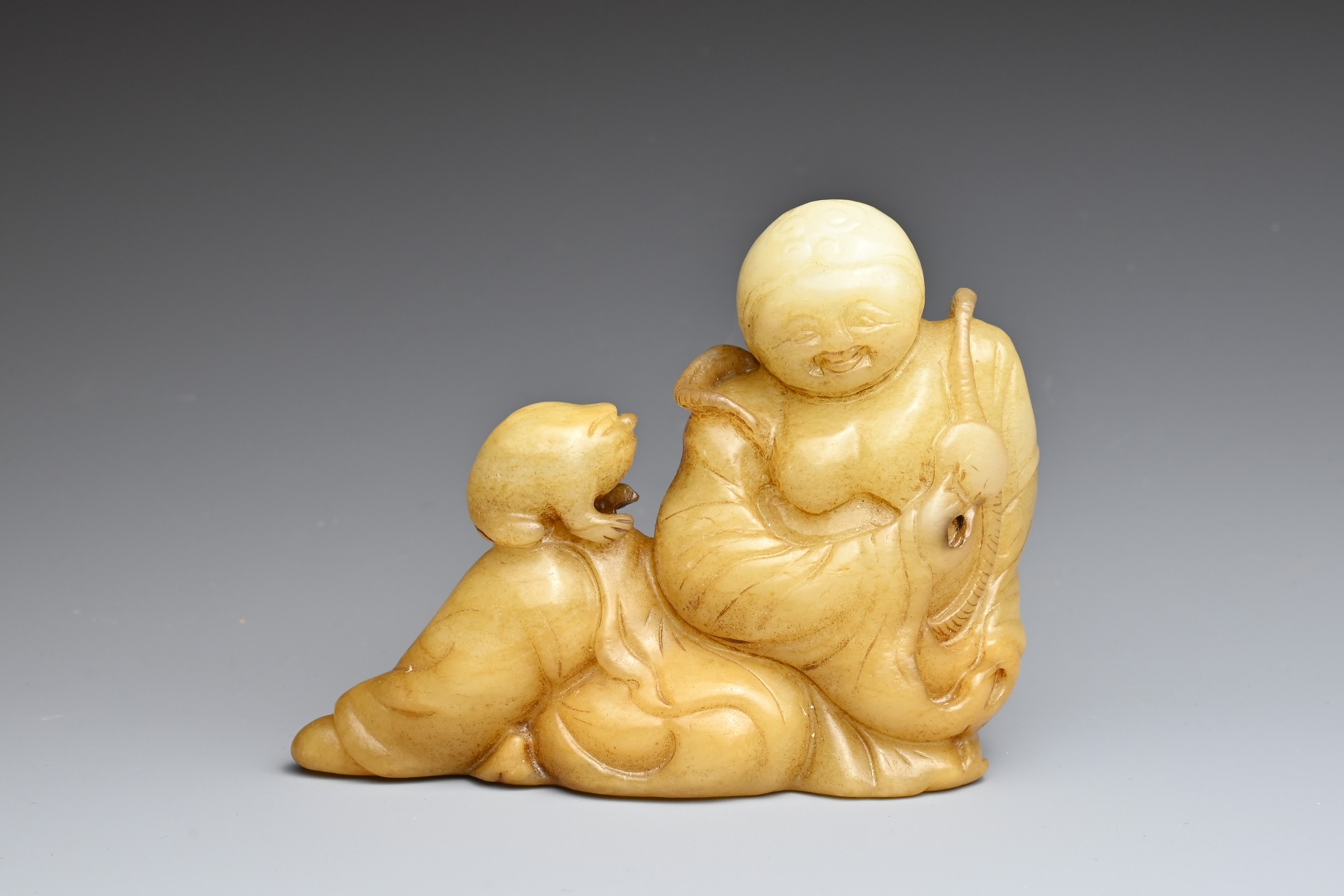 A CHINESE JADE CARVING OF LIU HAI AND TOAD. The figure reclining holding a cash coin and the toad on