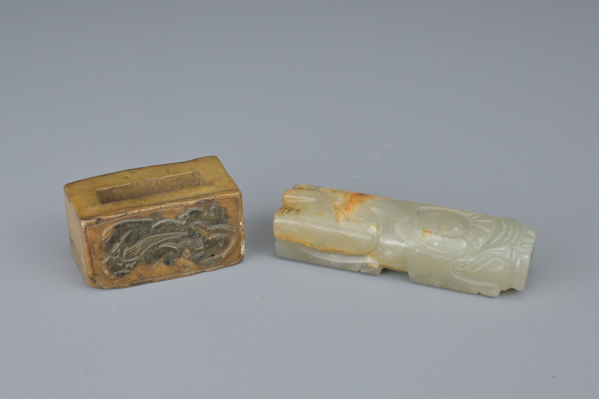 TWO CHINESE JADE FITTINGS. To include a celadon and russet animal form section of cylindrical