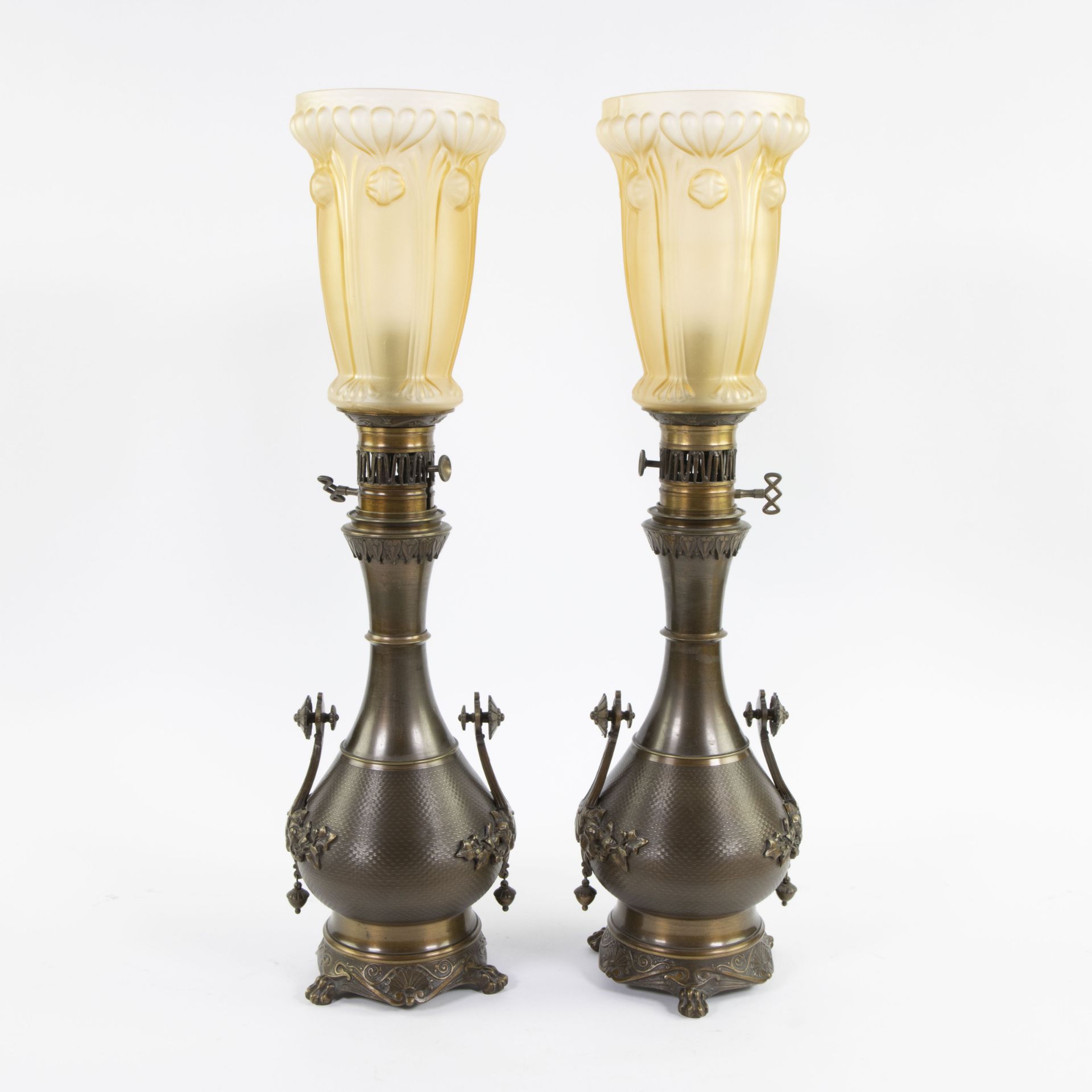 Pair of oil lamps in finely worked brass and fine glass shades marked at the bottom with initials JS