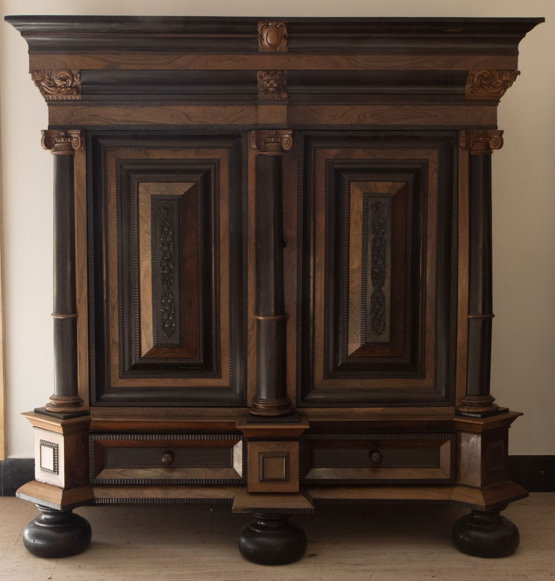 Ranaissance cabinet period 1600-1620 with paneled doors and blackened frames under a decorated corni