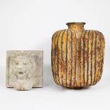 A stone lion head and a metal jug