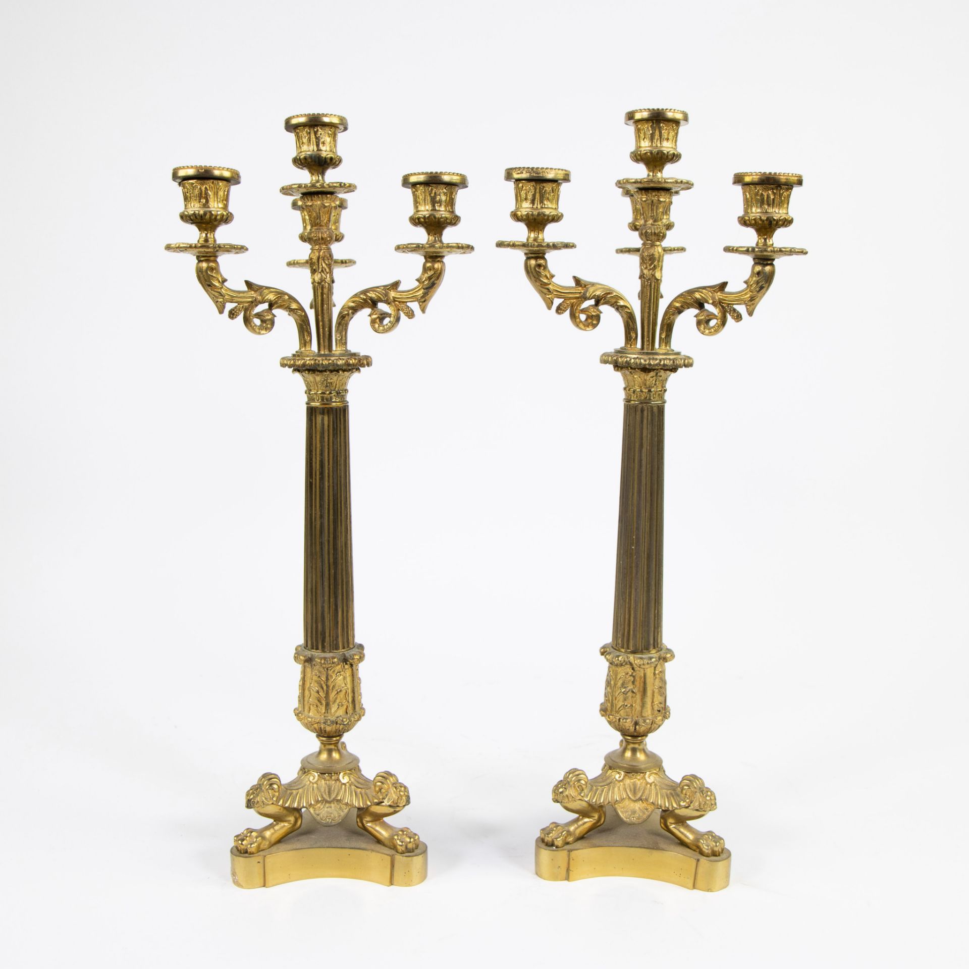 A pair of gilt bronze candlesticks with four light points and on three lion's feet.