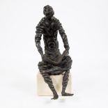Bronze sculpture of a reading character on a white marble base
