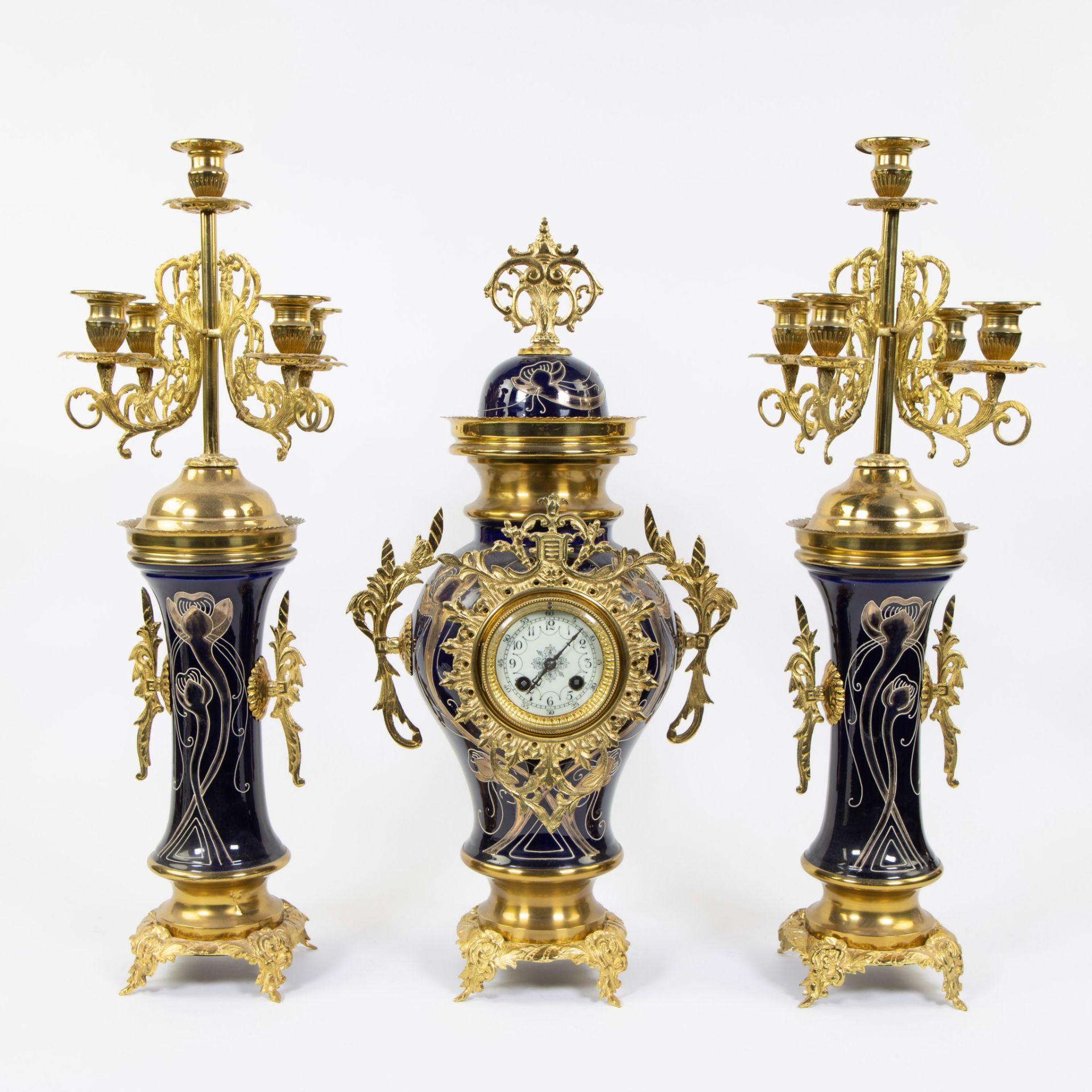 Three piece faience garnish decorated with stylized whiplash motifs and gilt brass, candlesticks wit