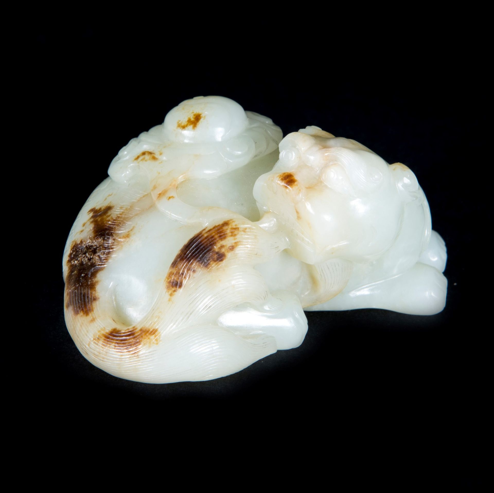 A WHITE JADE AND RUSSET LION DOG l. 8 cm